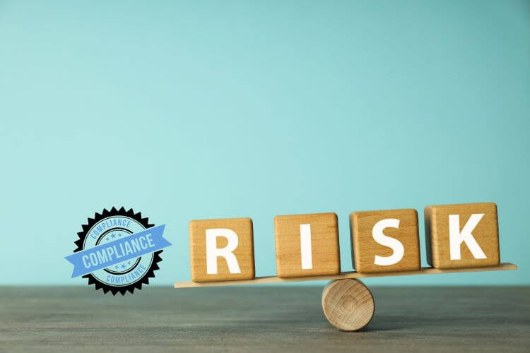 A wooden balance with the word RISK on one side.