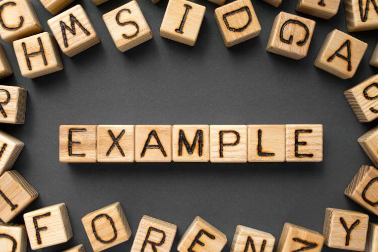 Wooden letter blocks spelling "EXAMPLE" are centered on a dark surface,