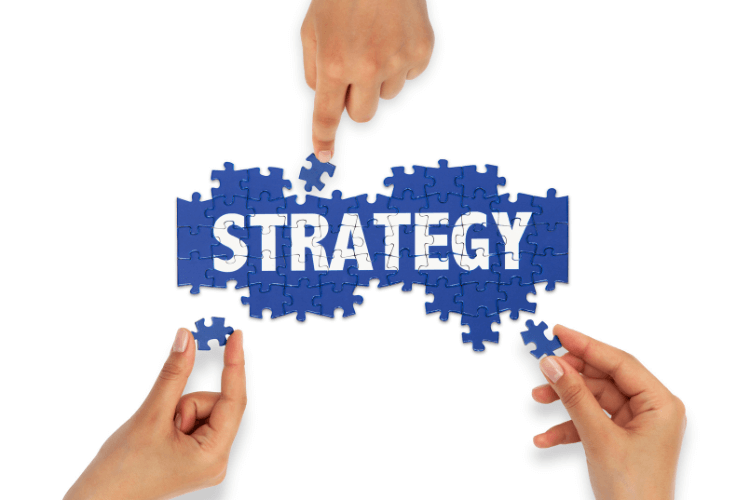 Hands assembling puzzle pieces spelling 'Strategy,' symbolizing collaborative planning and growth tactics