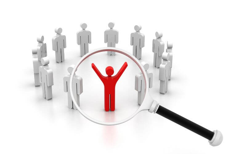Magnifying glass focusing on red figure among group, symbolizing targeted marketing and customer segmentation