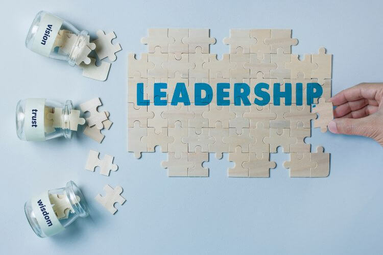Leadership concept with puzzle pieces and jars labeled vision, trust, and wisdom on a light blue background