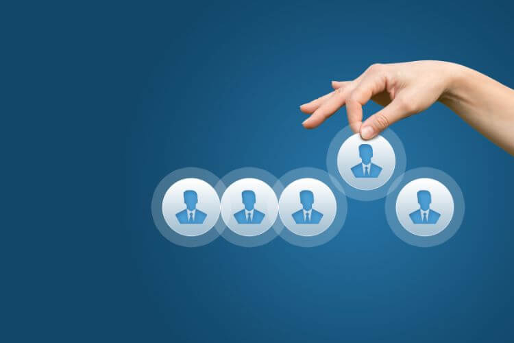 Hand selecting the best candidate from a row of business icons for targeted marketing attribution.