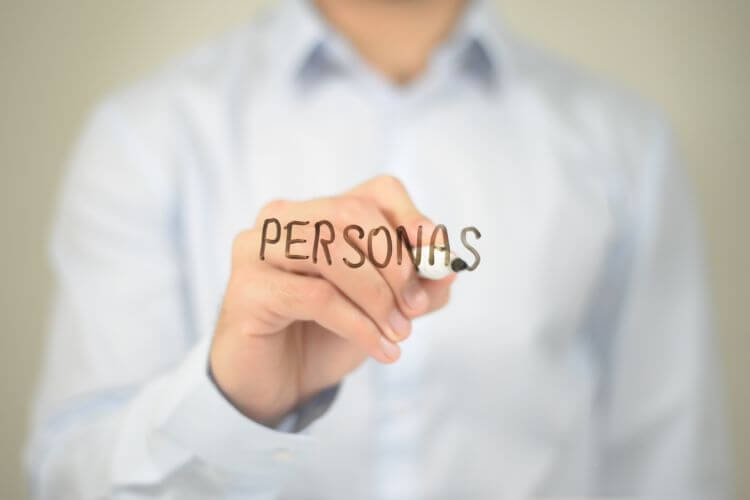 Person writing “Personas” to illustrate traditional approach to audience segmentation and customer profiling.